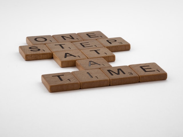 Scrabble letters spelling 'One step at a time'